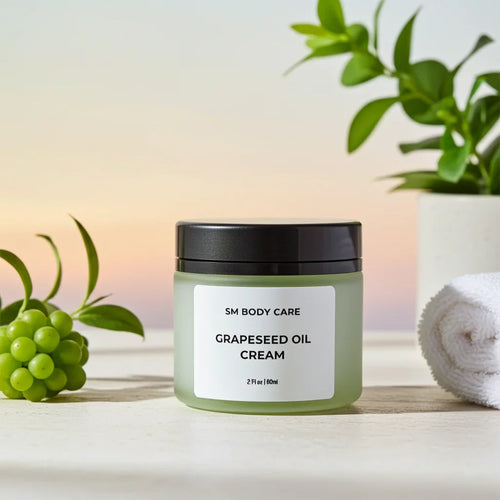 SM Body Care Grapeseed Oil Cream jar with black lid on a light surface, green grapes and white towel nearby